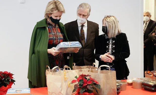 Queen Mathilde wore a wild tartan shirt dress by CH Carolina Herrera, and a green wool cashmere coat by Natan. Caritas Secours