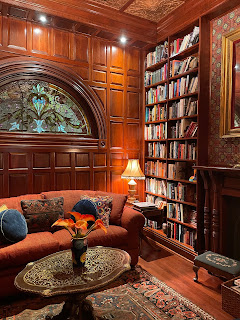 Heather Young's beautiful wood-panelled library with floor to ceiling shelves of books and a comfy chair.