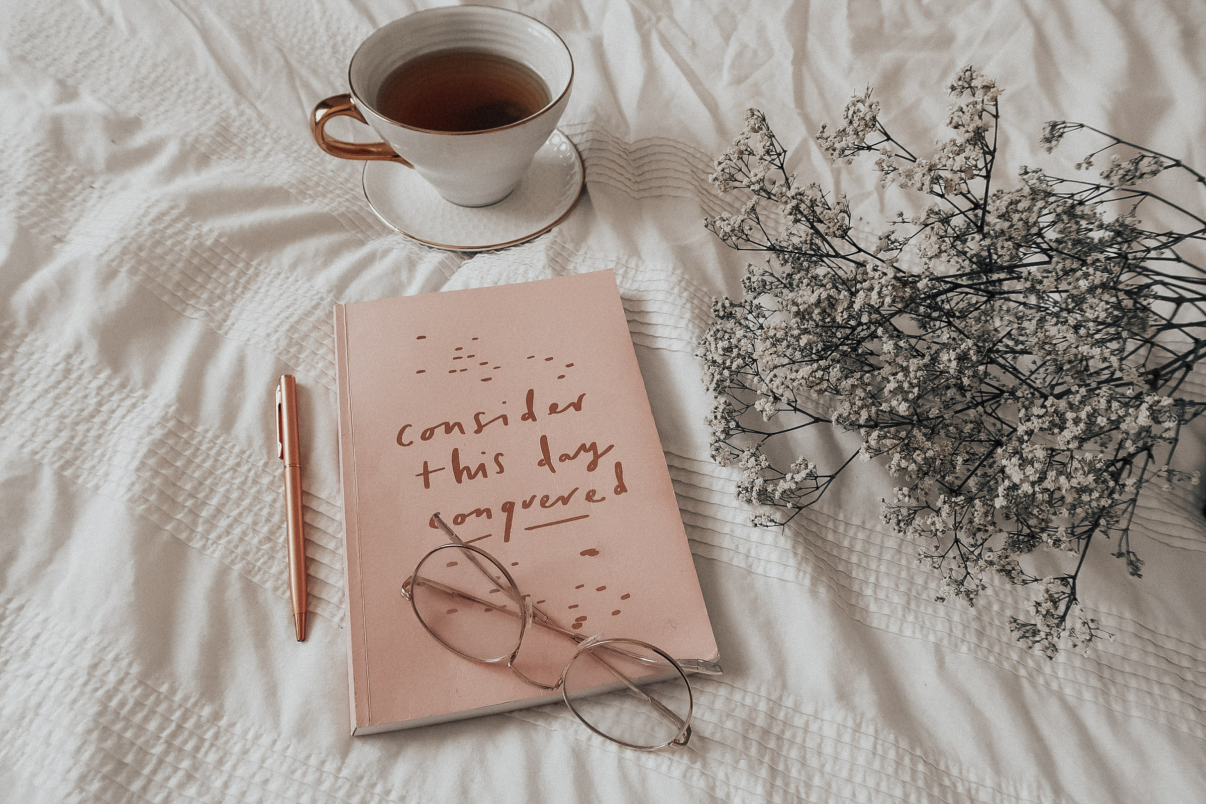 A pink planner and a white mug.