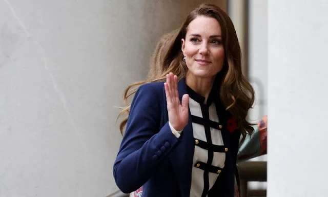 The Duchess wore a dark blue wool coat by Catherine Walker, and a white and navy military style blouse by Alexander McQueen