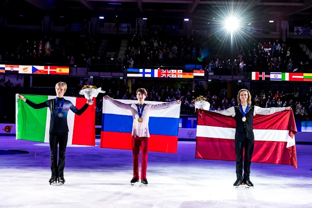 Grassl, Kondratiuk e Vasijevs posam para foto com suas medalhas. Eles seguram as bandeiras dos seus países