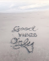 Good vibes only written in sand at the beach