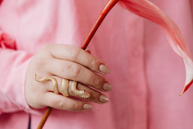 Close up of a snake-shaped ring while being worn by a pink shirt-wearing person.