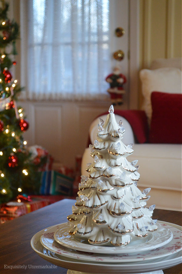 White Ceramic Christmas Tree on a table in front of the tree