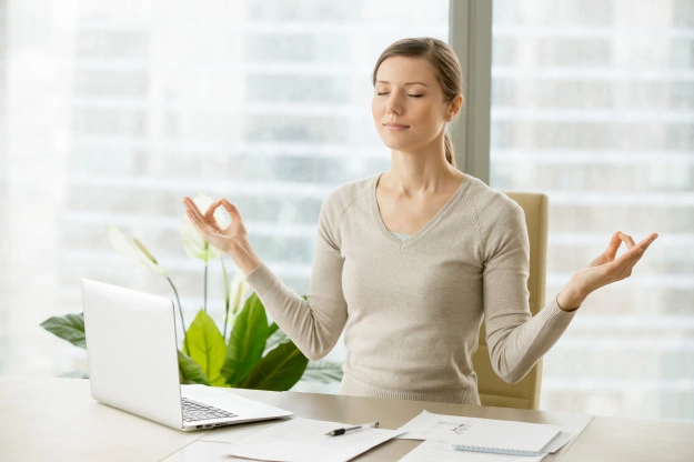 Mulher em postura de meditação sentada no escritório