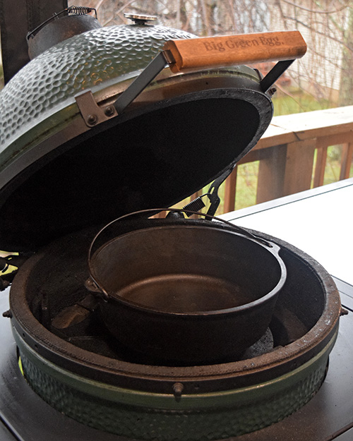 Big Green Egg set up for cooking with a camp style dutch oven
