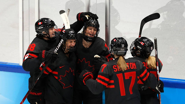 Canadenses se abraçam comemorando um gol