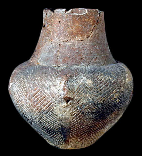 Πήλινο κρατηρόσχημο αγγείο με διάτρητες αποφύσεις για ανάρτηση και εγχάρακτη γραμμική διακόσμηση. Το άνω τμήμα συμπληρωμένο με γύψο. 3200-2800 π.Χ.