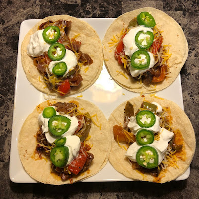 Steak fajita tacos, topped with cheese, sour cream and some fresh jalapeno