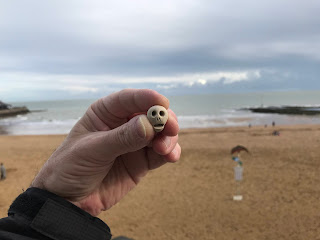 A picture of a small, ceramic skull (Skulferatu #58) being held with a view of the beach at Viking Bay, Broadstairs behind it.  Photo by Kevin Nosferatu for the Skulferatu Project.