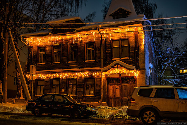 Деревянное, двухэтажное здание в новогодней подсветке