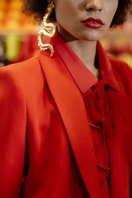 A person in a red suit modeling a chunky dragon-shaped gold earring.