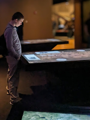 a boy looks solemnly at a horizontal video display table at the National WWI Museum