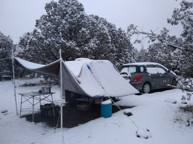 snow on tarps and trailer and car