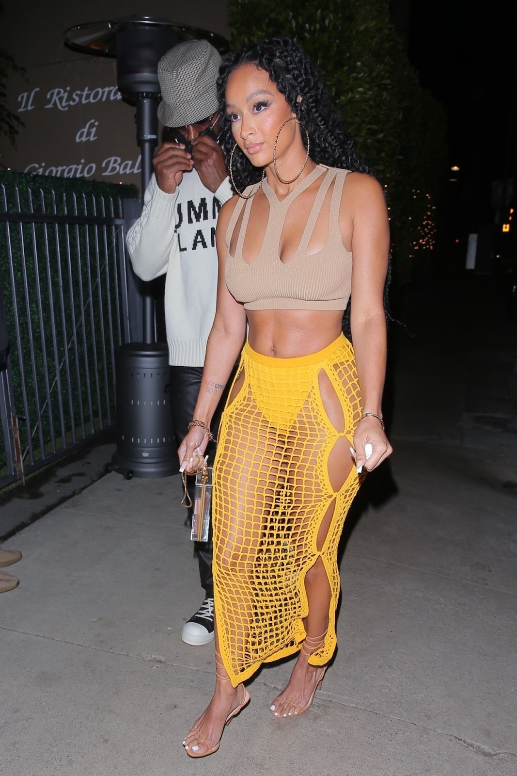 Draya Michele shows her curvy figure in a cropped top and yellow fishnet skirt in Santa Monica.