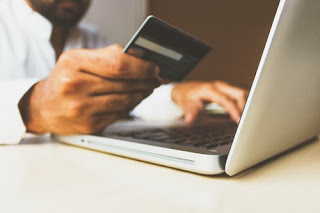 A man working on a laptop while holding an ATM card