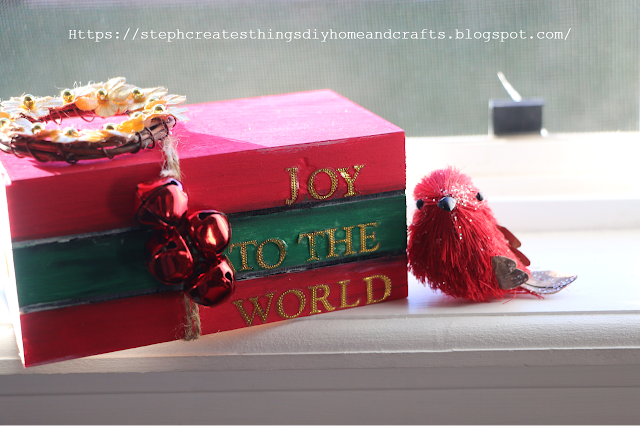 Completed Christmas wooden book stacked displayed on windowsill near faux red bird.