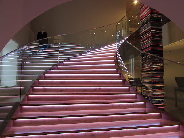 escada rosa toda iluminada e uma pilha de tecidos ao lado