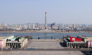 Kuzey Kore'nin merkezi kütüphanesi olan Büyük Halk Eğitim Evi'nden Kim İl-sung Meydanı'nda yer alan Kore Merkezi Tarih Müzesi (solda) ve Kore Sanat Galerisi (sağda) ile birlikte Juche Kulesi'nin görüntüsü