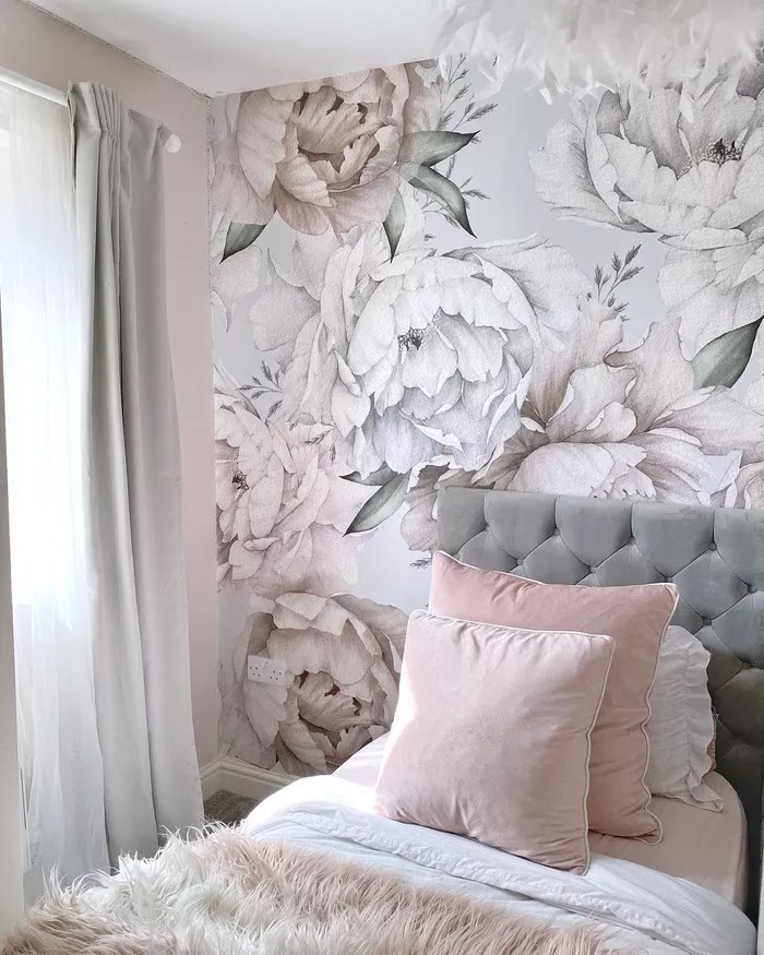 Bir genç kızın yatak odasında sessiz gri ve pembe tonlarda büyük çiçek baskılı duvar kağıdı.