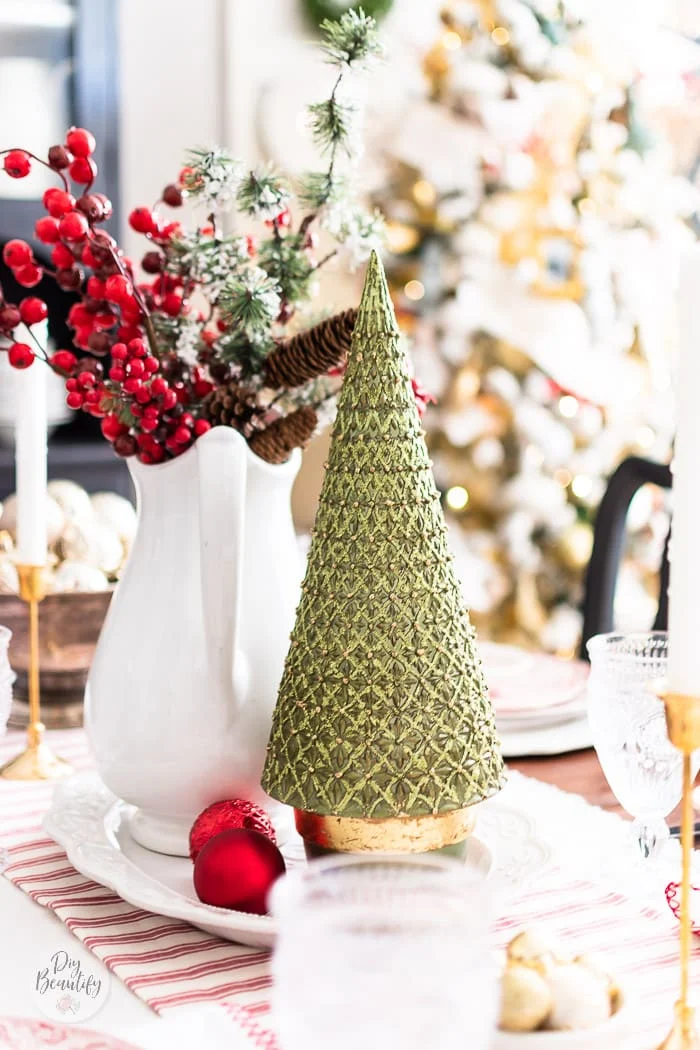 Christmas table centerpiece green and gold tree, ironstone pitcher filled with red berries, ornaments all sitting on white platter