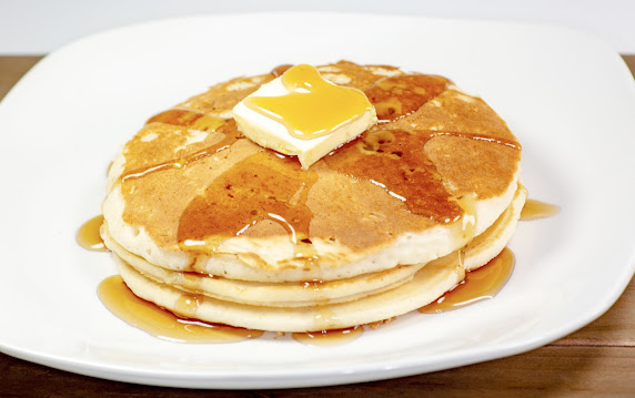 Photo on white plate of buttermilk pancakes with maple syrup