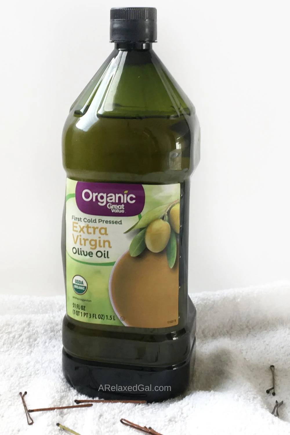 tall green bottle of cold pressed extra virgin olive oil being used on relaxed hair.