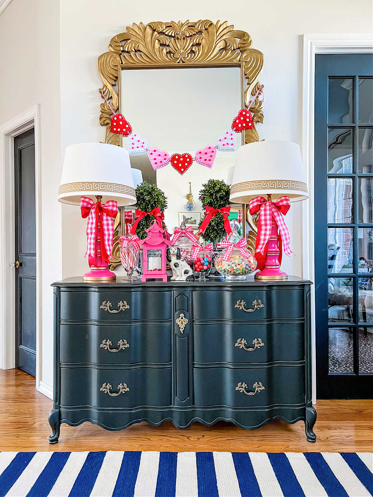 Entry Valentine's Day decorations- black dresser with candy in apothecary jars and heart garland over mirror