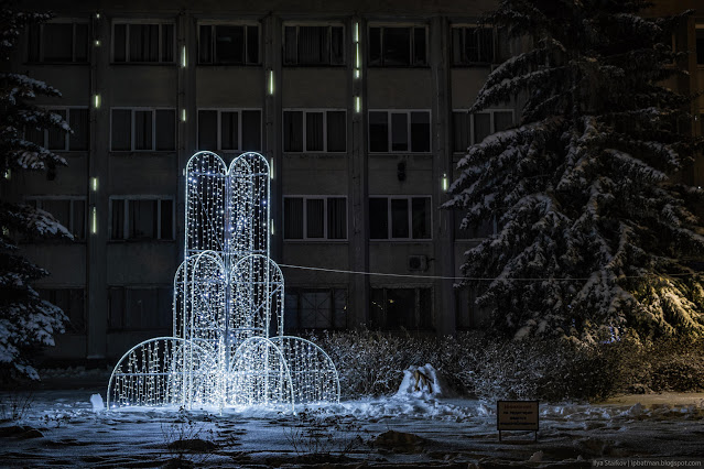 Световой фонтан на фоне здания с падающими снежинками