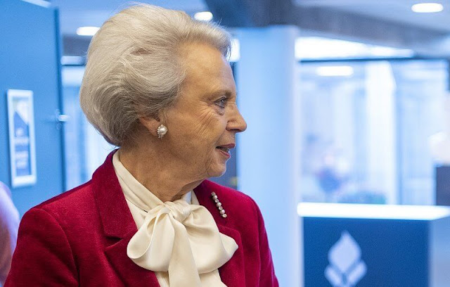 Princess Benedikte wore a red velvet blazer, and an ivory silk bow blouse. She wore a print midi skirt. Pearl brooch and pearl earrings