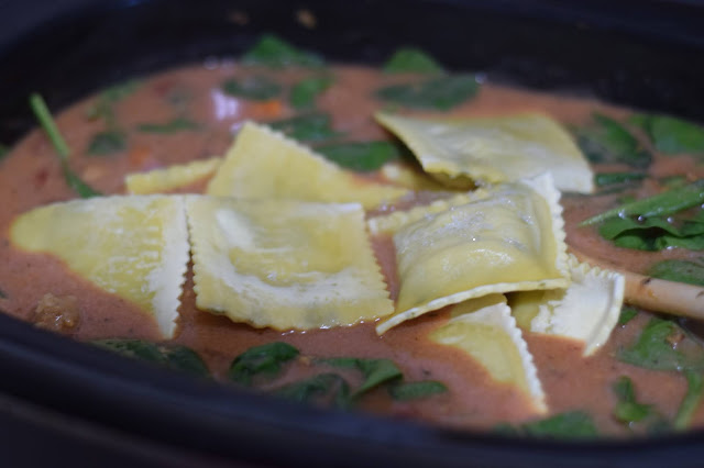 The frozen vegan ravioli being added to the slow cooker.