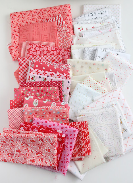 Scrappy pink and low volume background fabrics in a stack for a scrappy heart quilt block