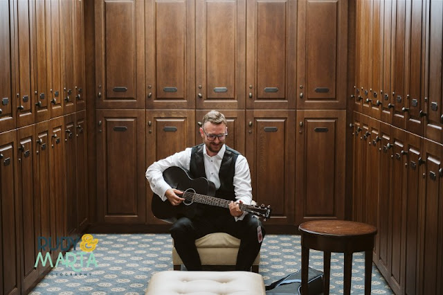 groom in suit playing on guitar