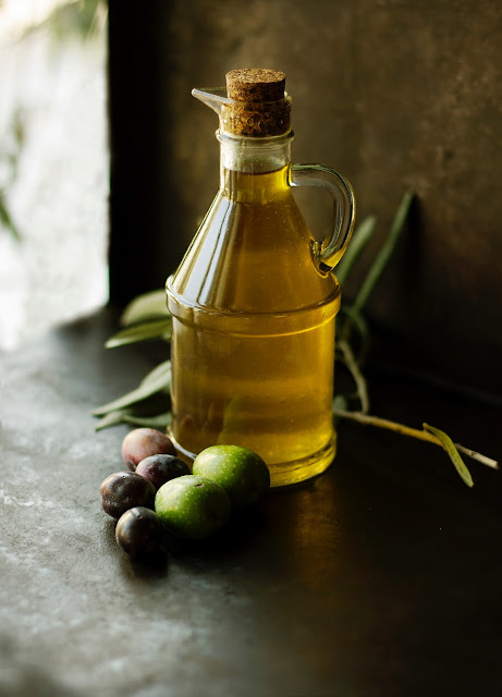 Olive oil in glass flask with olives on table:Photo by Roberta Sorge on Unsplash