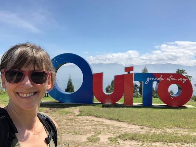 woman in front of Quito city sign