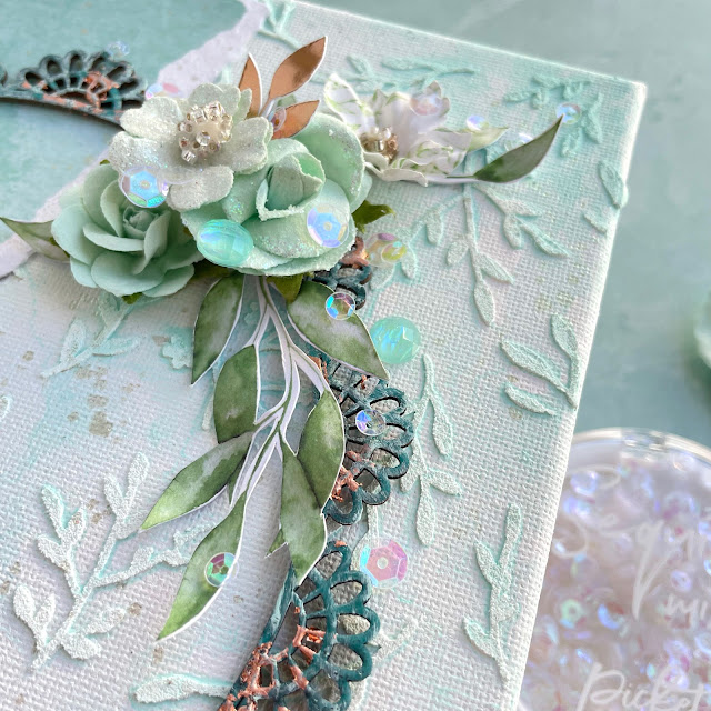 Mixed media canvas made with: Prima watercolor floral paper, paper flowers, gems, chipboard, Finnabair impasto paint, metallic flakes copper, indigo metal charms; Tim Holtz salvaged patina glaze and paint; Picket Fence iridescent moonshine sequins