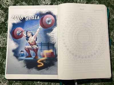 A journal with Wonder Woman squatting with a barbell over her head the caption above her read 2018 goals