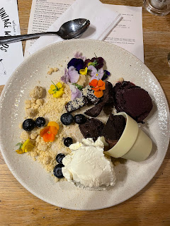 A plate of food - scoops of ice cream, mouse, brownie chunks, sorbet, edible flowers and biscuit crumbs.