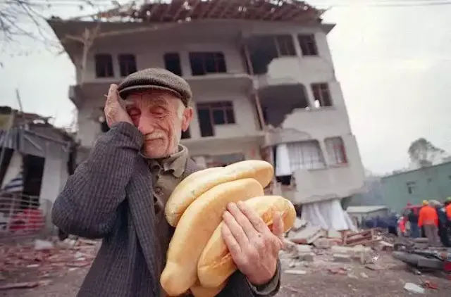 depremde yıkılan evinin önünde ekmek tutan, ağlayan yaşlı amca