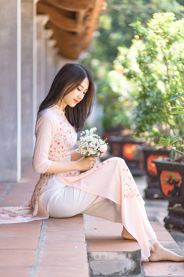 Thiếu nữ ngồi áo dài hoa ôm hoa