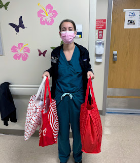 Air Force 2nd Lt. Kristen Bishop in scrubs holding three red bags full of essential supplies.
