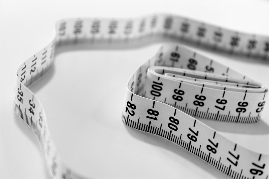 A white weight loss measuring tape with blake indications on it lying on a white surface