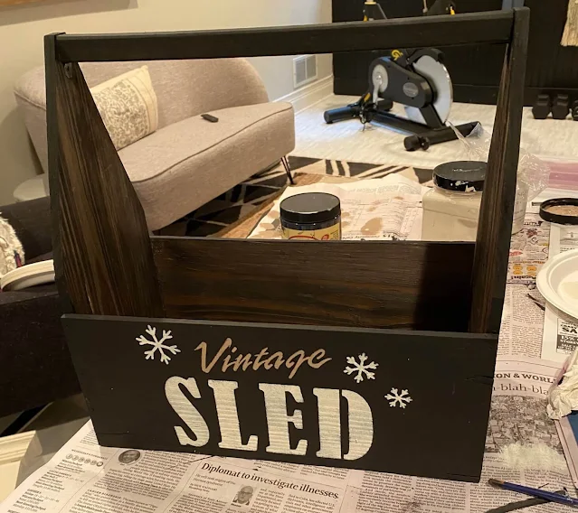 Photo of a thrifted toolbox/tote painted black & stenciled with a Vintage Sled Company Stencil from Old Sign Stencils.