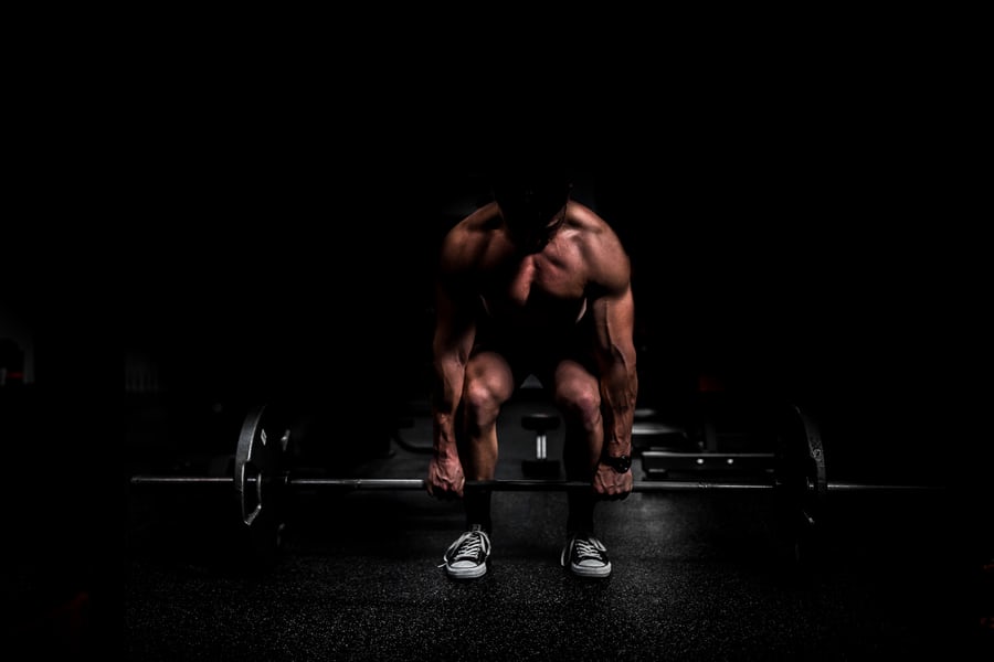 A muscled white man about to lift weights in order to lose weight