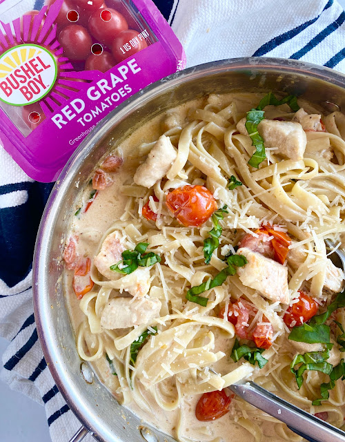 Skillet & plastic container of Bushel Boy tomatoes showcasing a rich pasta dish.