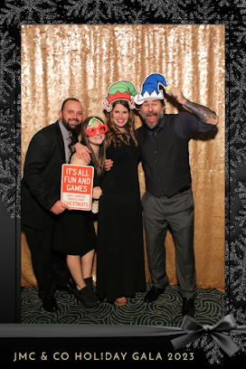 Man holding sign, woman in holiday glasses, woman with hat on, man with hat on in phot booth
