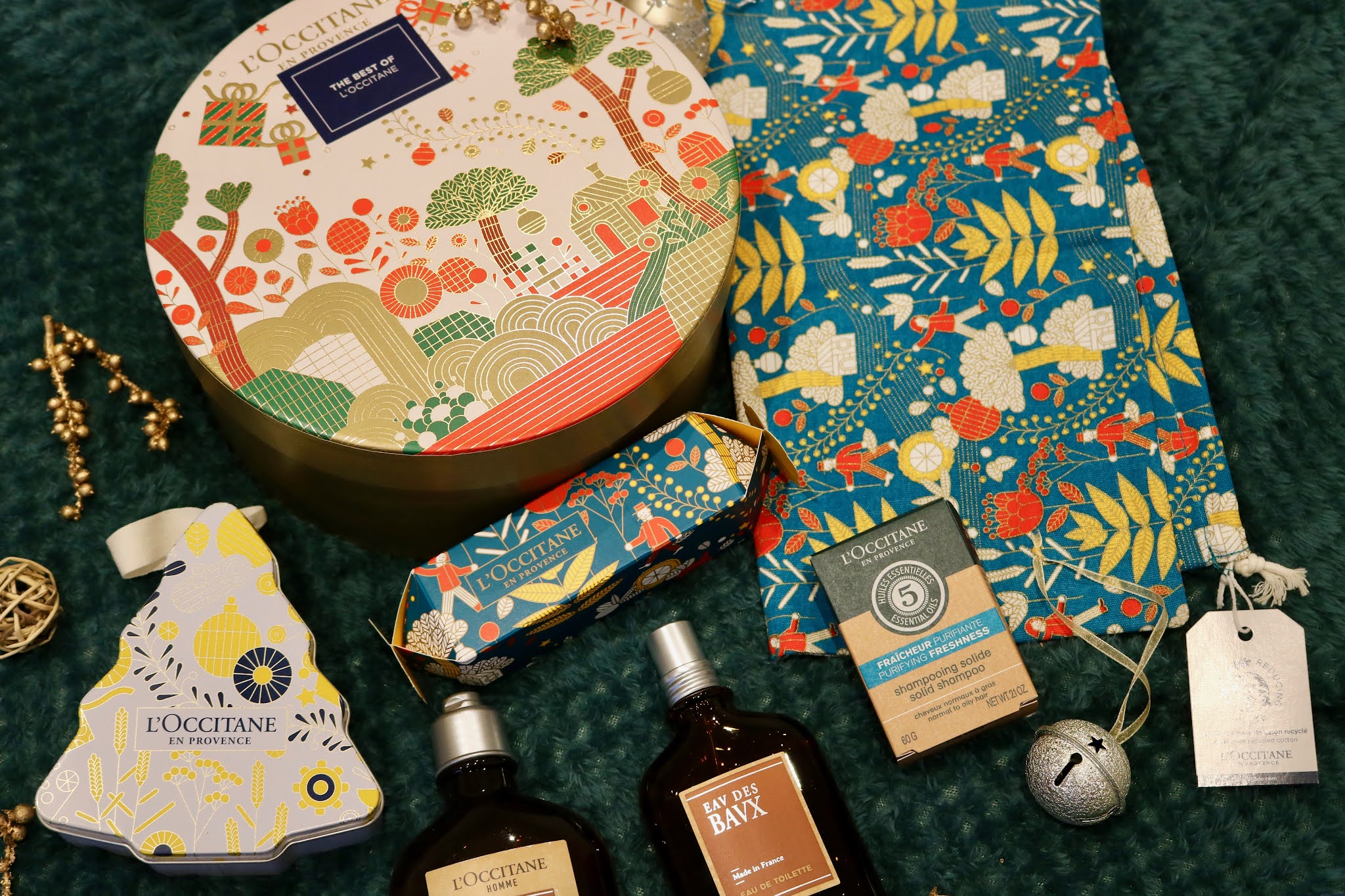 Selection of L'Occitane gift sets on a green blanket surrounded by gold Christmas decorations