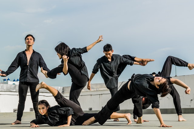 6 boys and girls in black dress are doing yoga together