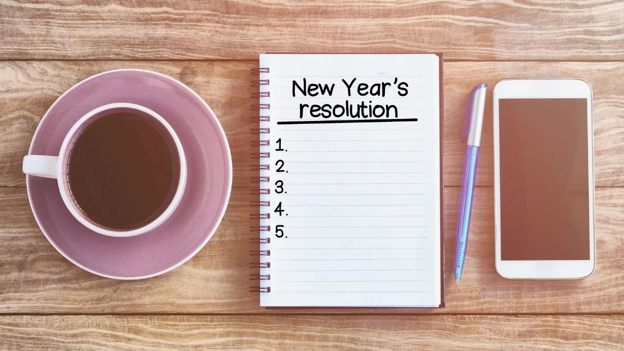 New year's resolution list on note pad, wood table with coffee, pen and smart phone retro styled.