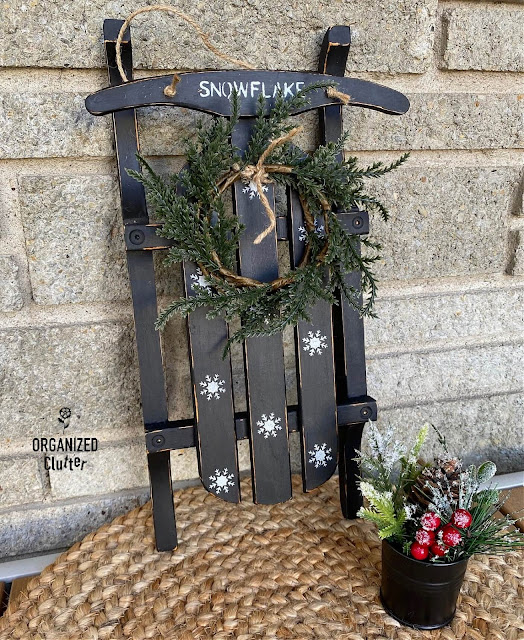 Photo of a small sled painted black with snowflake stenciling.